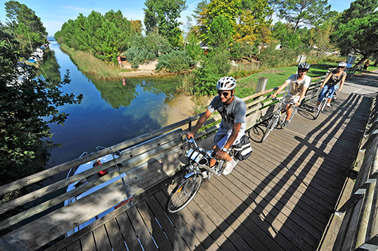 Radfahrer fahren über eine kleine Holzbrücke in Les Landes.