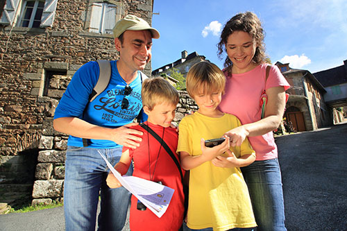 Eine Familie mit zwei Kindern beim Geocaching in einem französischen Dorf